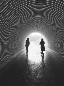silhouette of man and woman walking in tunnel